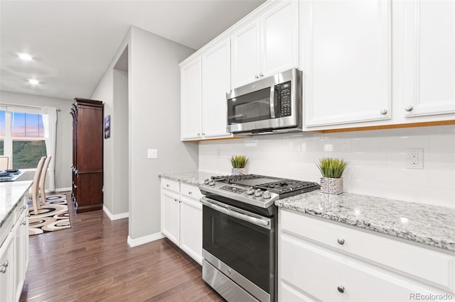 18922 W 84th Ave, Arvada, CO 80007 - kitchen featuring baseboards, dark wood-type flooring, white cabinetry, appliances with stainless steel finishes, and backsplash