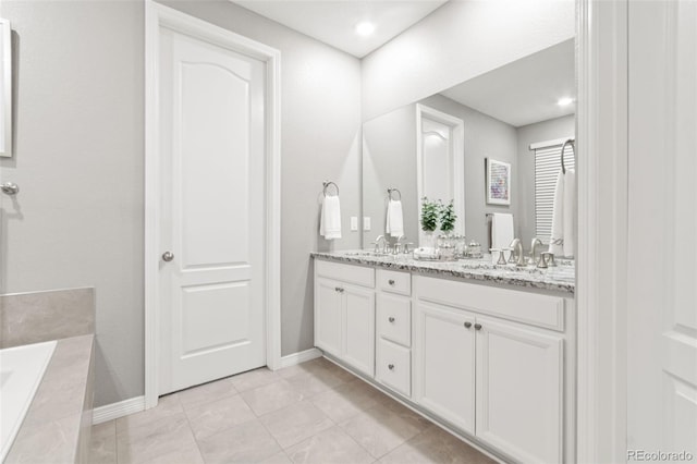 18922 W 84th Ave, Arvada, CO 80007 - bathroom featuring double vanity, a washtub, baseboards, tile patterned floors, and a sink