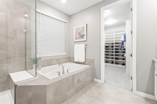 18922 W 84th Ave, Arvada, CO 80007 - bathroom with a tile shower, a walk in closet, tile patterned flooring, baseboards, and a bath