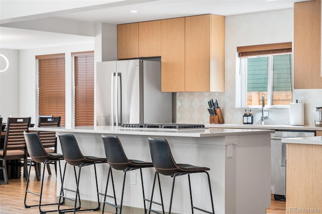 4966 Knox Ct, Denver, CO 80221 - kitchen featuring appliances with stainless steel finishes, tasteful backsplash, a breakfast bar, light wood-style flooring, and recessed lighting