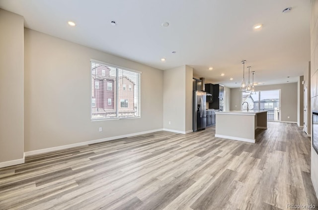 unfurnished living room featuring light wood-type flooring, plenty of natural light, and sink