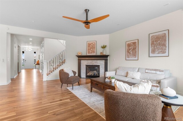 10546 Sundial Rim Rd, Highlands Ranch, CO 80126 - living room with light wood finished floors, stairway, ceiling fan, a stone fireplace, and baseboards