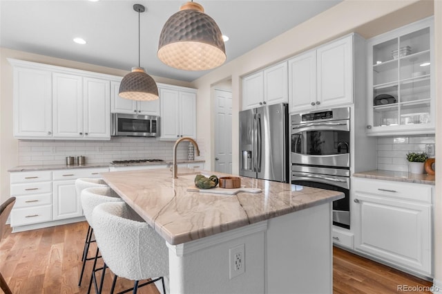 10546 Sundial Rim Rd, Highlands Ranch, CO 80126 - kitchen featuring stainless steel appliances, tasteful backsplash, light wood finished floors, white cabinets, and recessed lighting