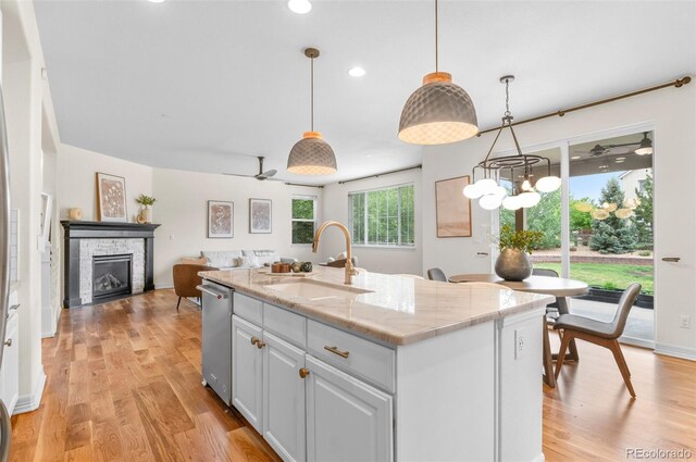 10546 Sundial Rim Rd, Highlands Ranch, CO 80126 - kitchen with a sink, dishwasher, light wood-style flooring, a stone fireplace, and recessed lighting