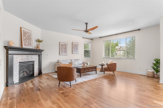 10546 Sundial Rim Rd, Highlands Ranch, CO 80126 - living room featuring light wood-type flooring, ceiling fan, a stone fireplace, and baseboards