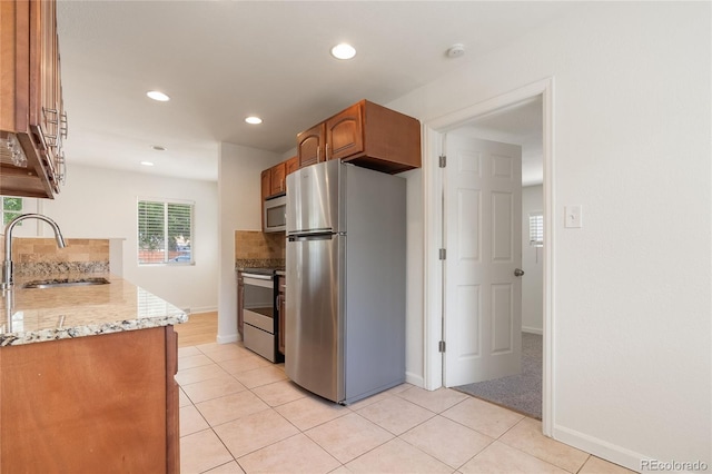 4972 W Custer Pl, Denver, CO 80219 - kitchen featuring appliances with stainless steel finishes, recessed lighting, light tile patterned floors, brown cabinets, and light stone counters