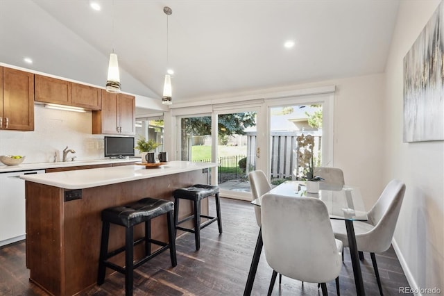 kitchen with dishwasher, lofted ceiling, backsplash, hanging light fixtures, and dark hardwood / wood-style flooring