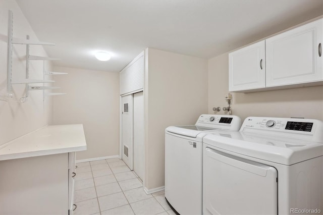 clothes washing area with cabinets, light tile patterned floors, and washer and clothes dryer