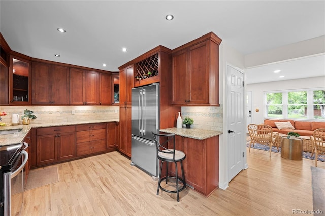 6402 Iris Ct, Arvada, CO 80004 - kitchen featuring stainless steel appliances, light wood-style floors, light stone counters, glass insert cabinets, and decorative backsplash
