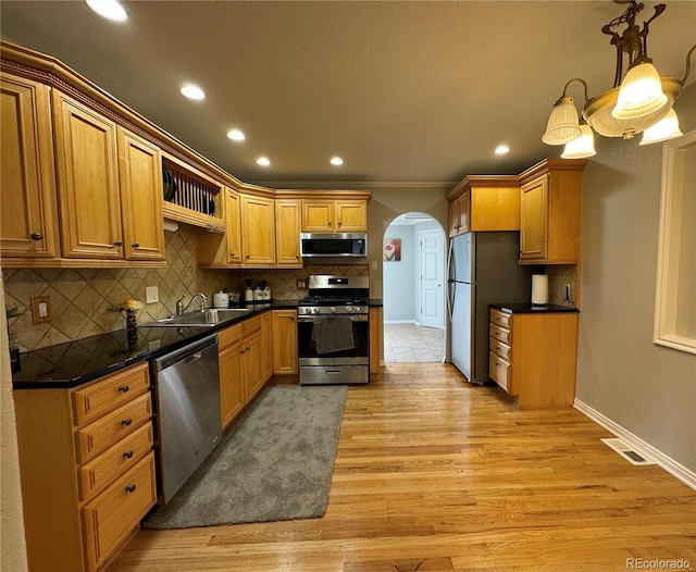 kitchen featuring pendant lighting, crown molding, sink, light hardwood / wood-style flooring, and stainless steel appliances