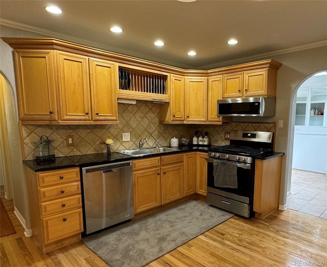 kitchen featuring sink, stainless steel appliances, backsplash, light hardwood / wood-style floors, and ornamental molding