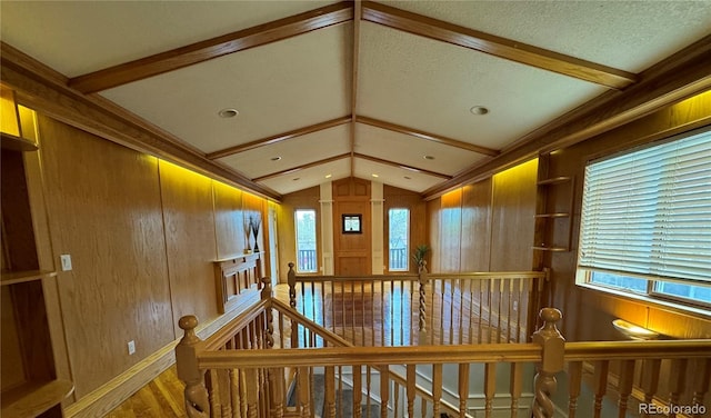 hallway with a wealth of natural light, wood walls, lofted ceiling, and hardwood / wood-style flooring