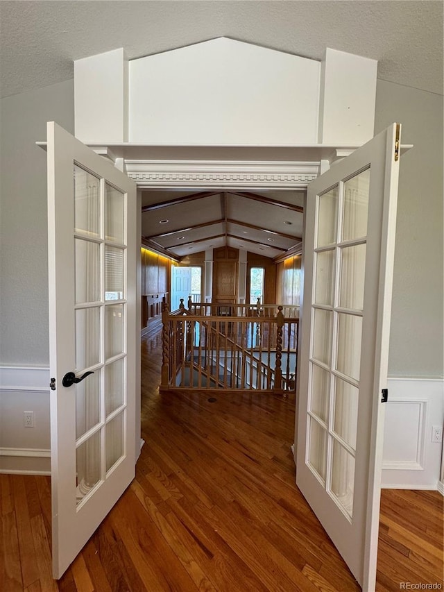 hall with french doors, hardwood / wood-style flooring, and vaulted ceiling