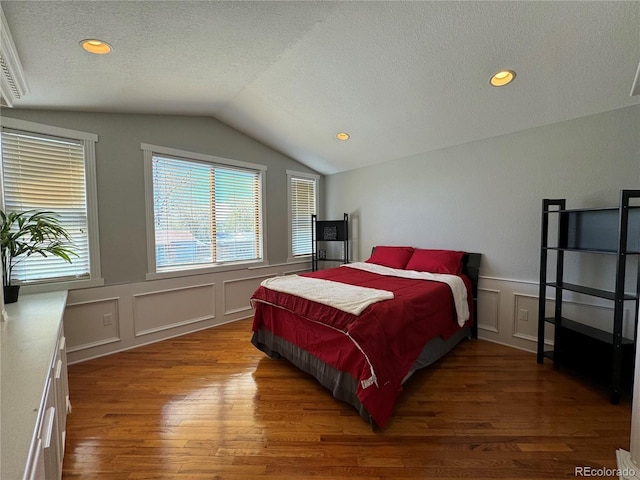 bedroom with dark hardwood / wood-style flooring, a textured ceiling, and lofted ceiling