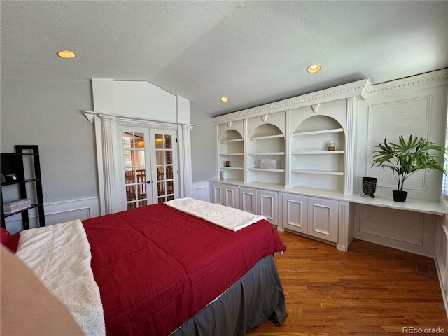 bedroom featuring a textured ceiling, french doors, light hardwood / wood-style floors, and lofted ceiling