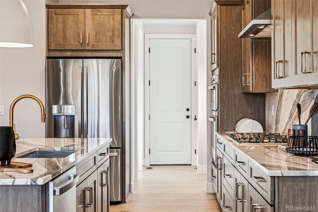 17146 W 92nd Loop, Arvada, CO 80007 - kitchen with a sink, wall chimney exhaust hood, appliances with stainless steel finishes, tasteful backsplash, and light wood-style floors