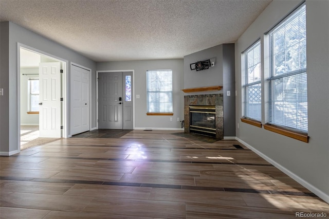 unfurnished living room with a textured ceiling, a healthy amount of sunlight, and a tiled fireplace