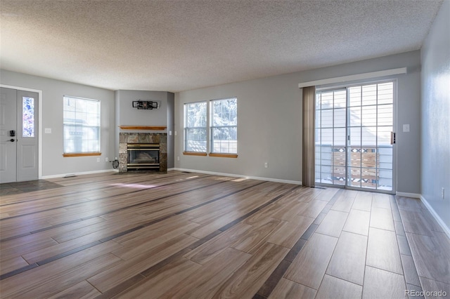 unfurnished living room with a fireplace, a textured ceiling, a healthy amount of sunlight, and wood-type flooring