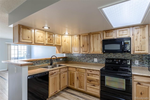 kitchen featuring light hardwood / wood-style flooring, sink, backsplash, black appliances, and kitchen peninsula