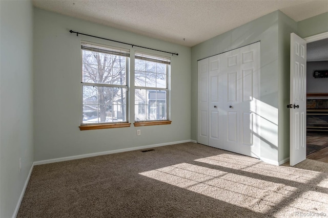 unfurnished bedroom with light carpet, a textured ceiling, and a closet