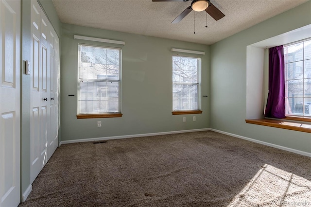 unfurnished room with a textured ceiling, carpet floors, and ceiling fan