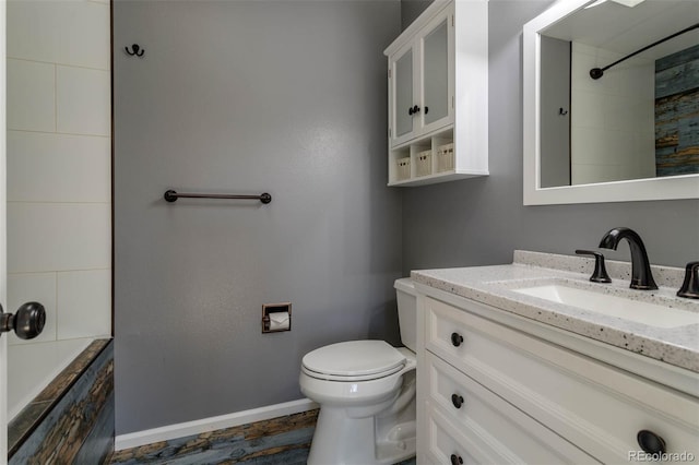 bathroom with a tile shower, vanity, and toilet