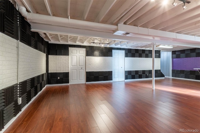 basement featuring wood-type flooring and brick wall