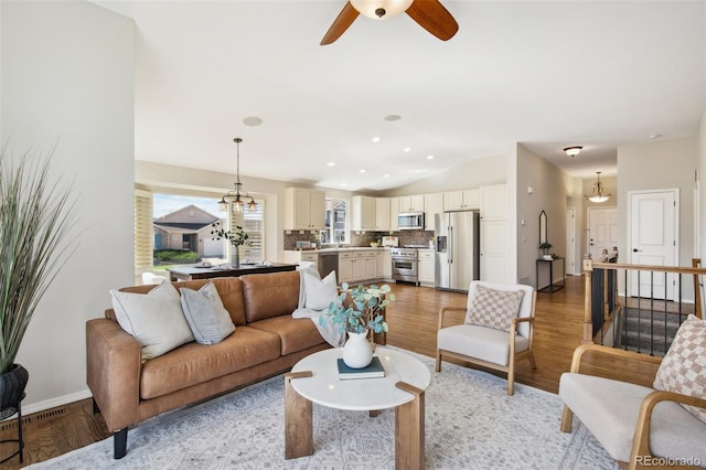 living area with lofted ceiling, ceiling fan, light wood finished floors, baseboards, and recessed lighting