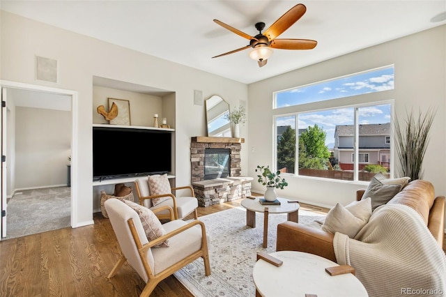 living room featuring a ceiling fan, wood finished floors, a fireplace, and baseboards