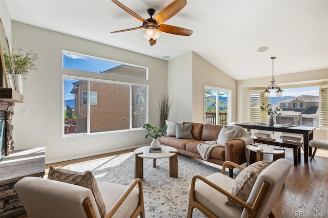 living room with wood finished floors, a ceiling fan, a fireplace, lofted ceiling, and baseboards