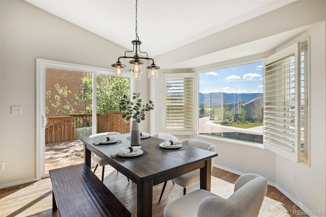 dining room featuring healthy amount of natural light, baseboards, wood finished floors, a mountain view, and lofted ceiling