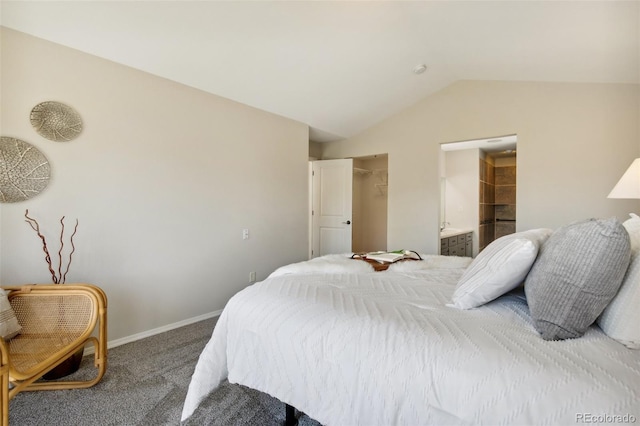 bedroom featuring carpet flooring, vaulted ceiling, ensuite bathroom, baseboards, and a spacious closet