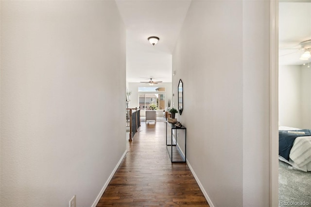 corridor featuring dark wood-type flooring and baseboards