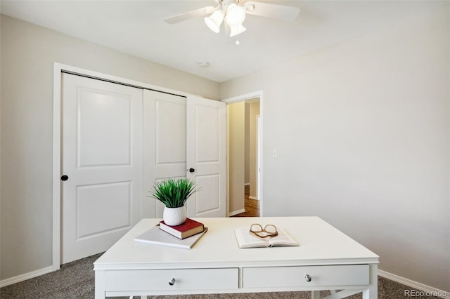 office area with baseboards, dark carpet, and a ceiling fan