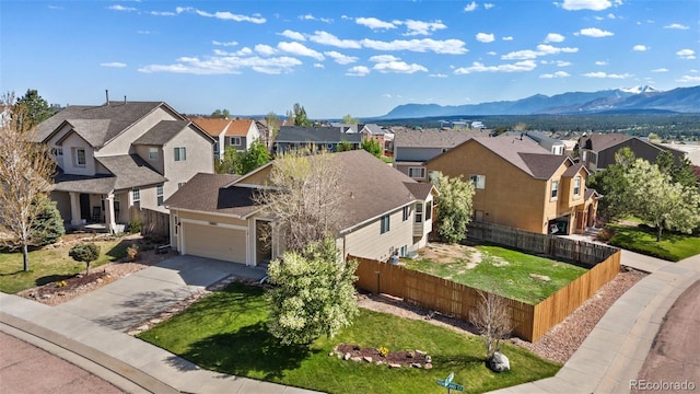 view of front of house with a residential view, an attached garage, fence, and a mountain view