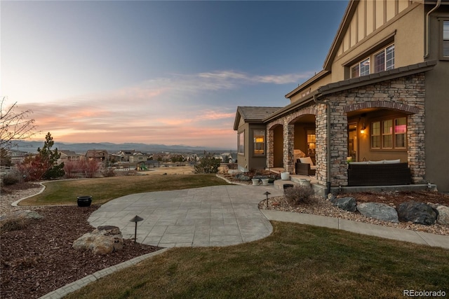 patio terrace at dusk featuring a yard