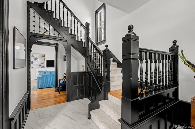 stairway with arched walkways, a towering ceiling, and marble finish floor