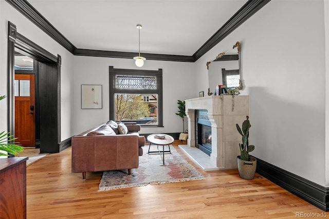 living area featuring a high end fireplace, light wood finished floors, baseboards, and ornamental molding