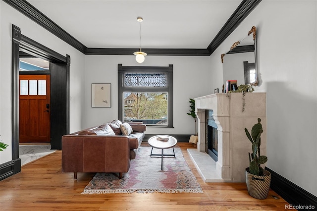 living area with light wood-style flooring, ornamental molding, a wealth of natural light, and baseboards