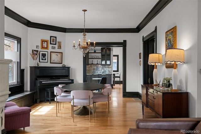 dining area with a chandelier, light wood finished floors, baseboards, and ornamental molding