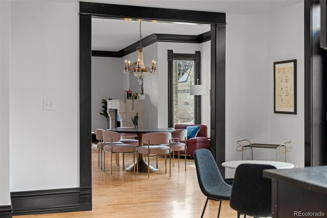 dining room featuring light wood-style floors, an inviting chandelier, and crown molding