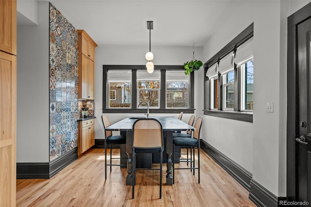 dining space featuring light wood finished floors and baseboards
