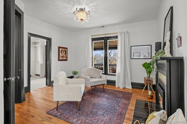 sitting room with visible vents, baseboards, an inviting chandelier, and wood finished floors