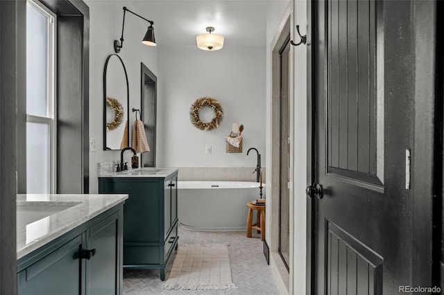 bathroom with a freestanding bath, two vanities, and a sink