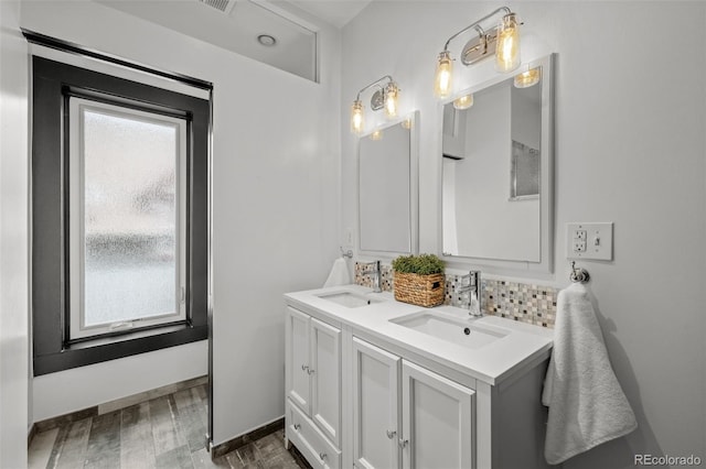 bathroom with wood finished floors, double vanity, a sink, and baseboards