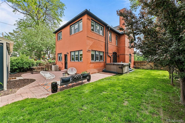 rear view of property with a hot tub, central AC, a yard, a patio, and fence