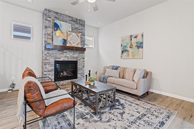 living room featuring wood-type flooring, ceiling fan, and a fireplace