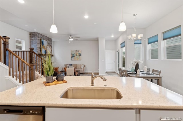 kitchen with an island with sink, dishwasher, sink, and hanging light fixtures