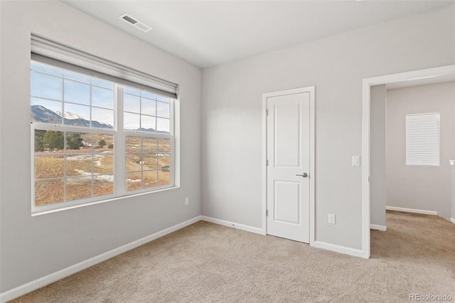 unfurnished bedroom featuring a mountain view and light carpet