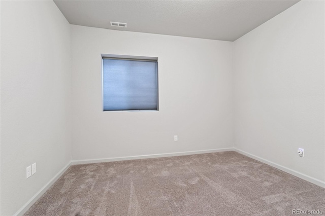 unfurnished room with light colored carpet and a textured ceiling